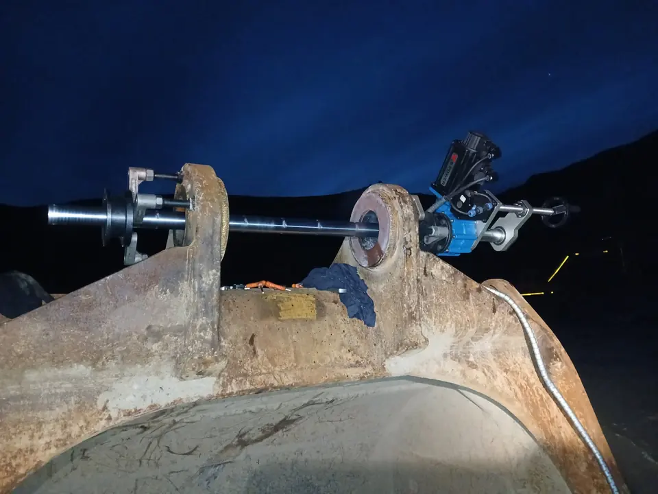 Line boring bar and drive unit rigged across a bucket after dark