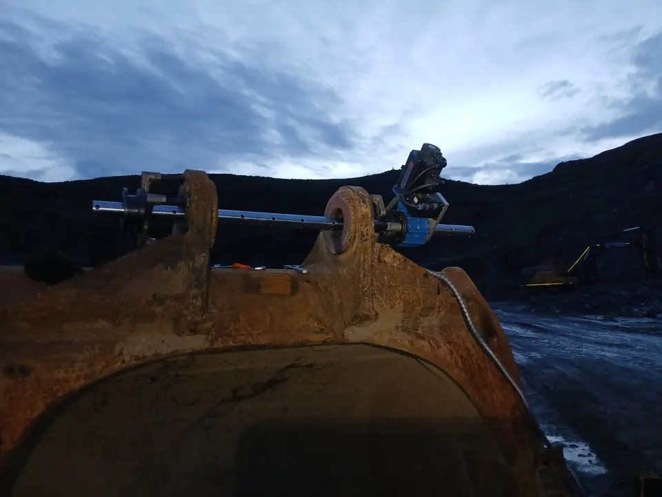 Line boring bar set up across a bucket at a quarry late in the day
