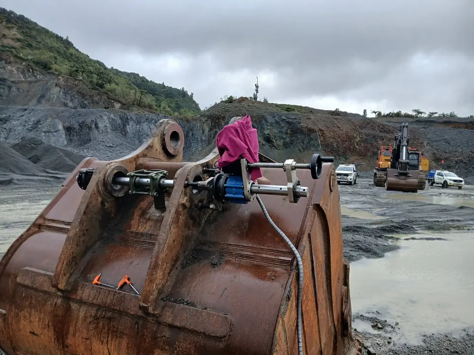 Line boring setup rigged across bucket lugs with a quarry face behind