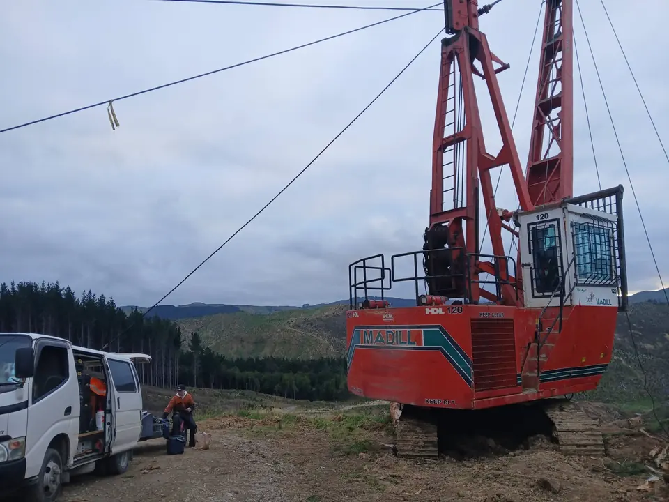 Forestry hauler tower on a hillside landing with service vehicles parked below