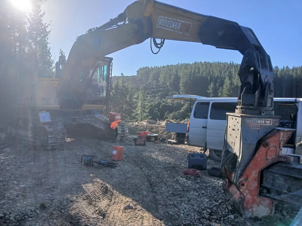 Tracked forestry machine on a landing with a service van parked behind it