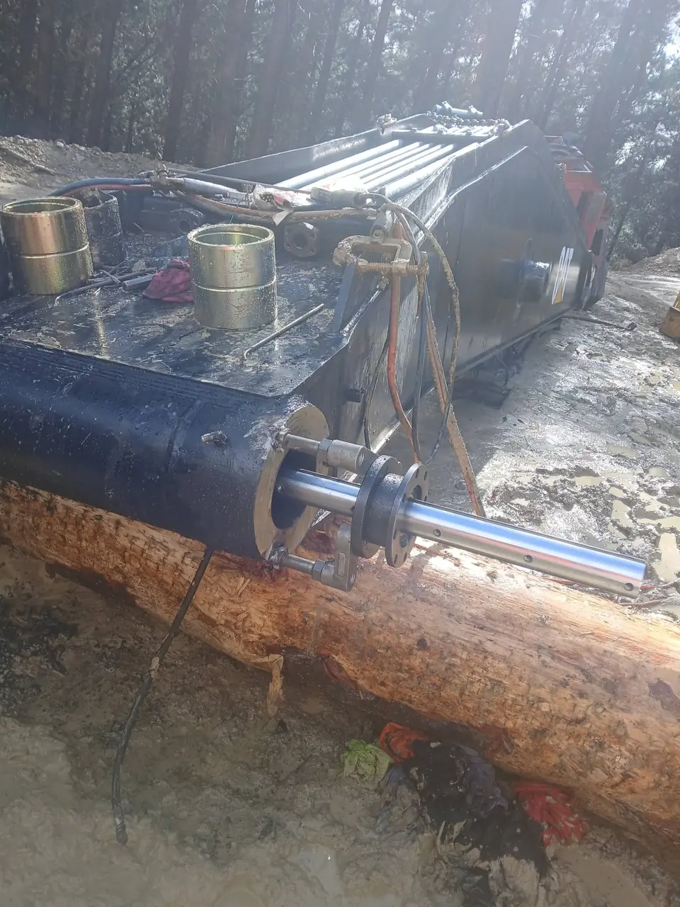 Pin and ram resting on timber blocks beside the machine