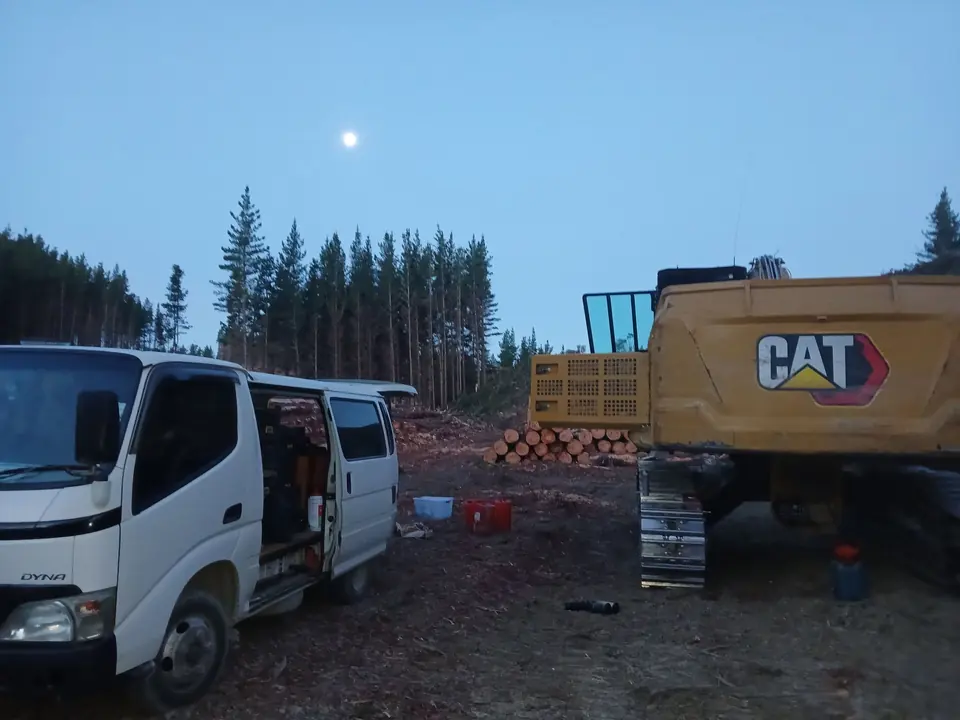 Service van parked beside a tracked machine at a forestry landing